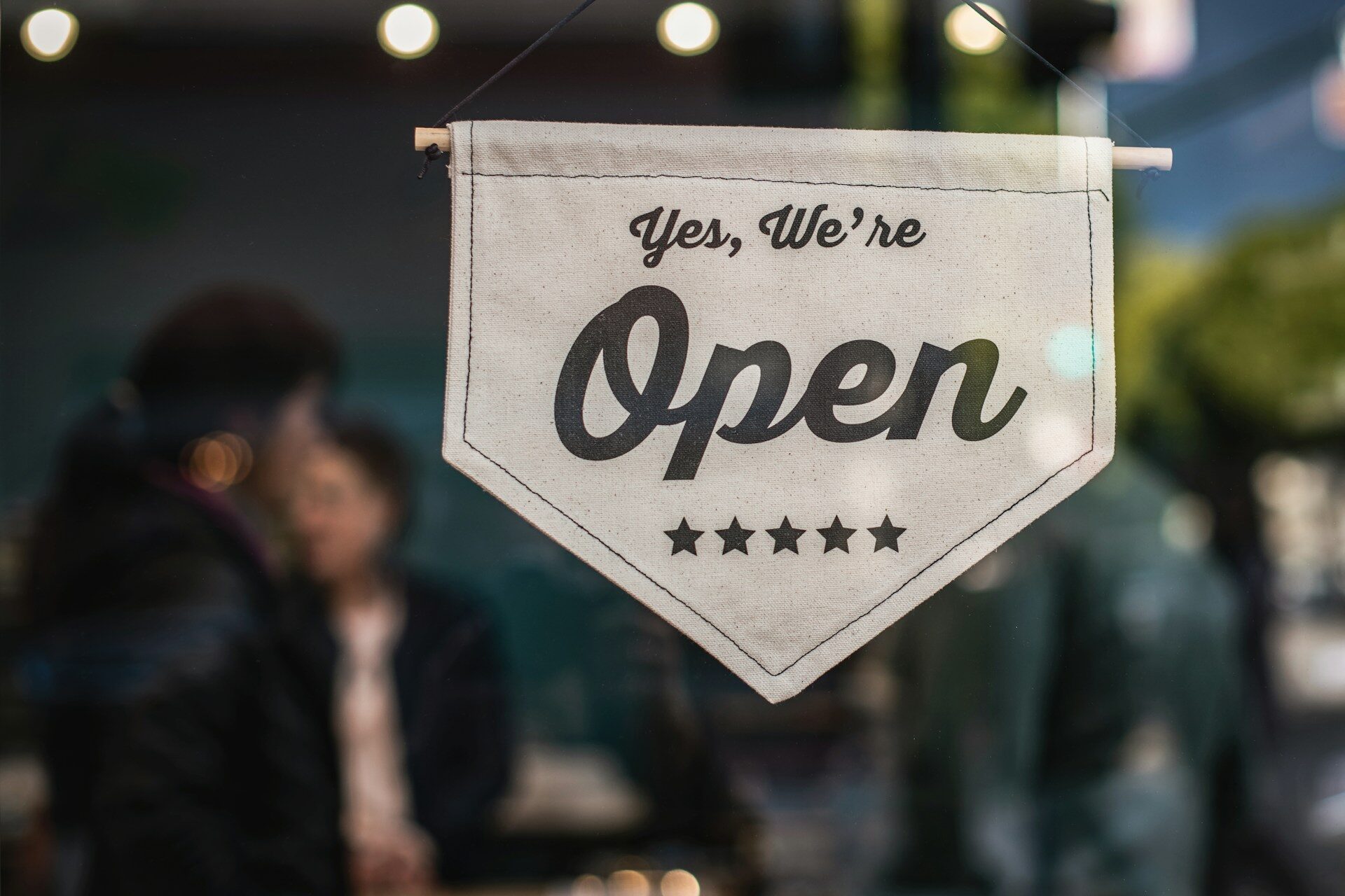 white sign that says “yes, we’re open” on a store window