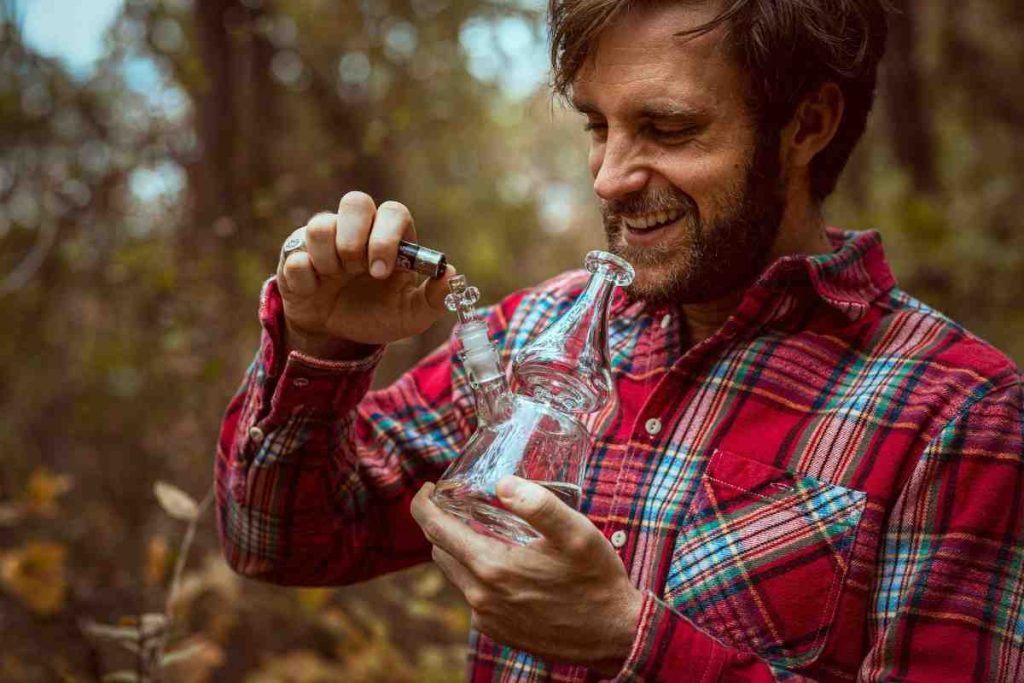 smiling man clear glass bong outdoor